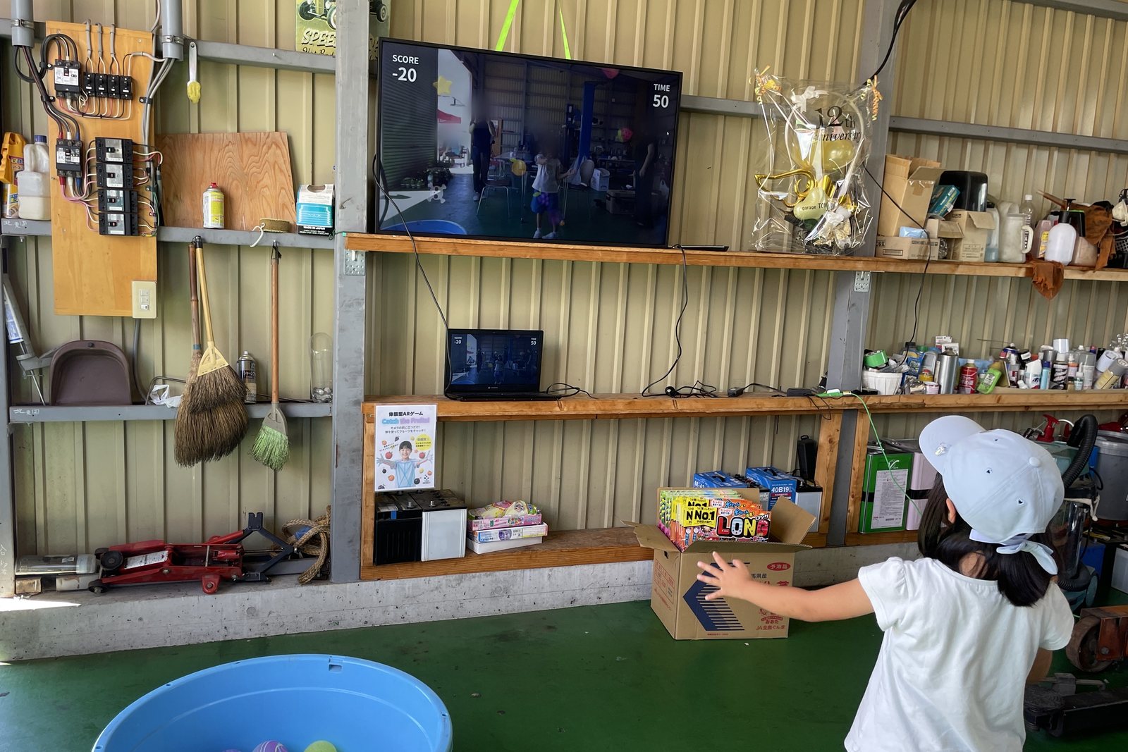 モニターの前で女の子が画面に手を伸ばし、体を動かしてARゲームを遊ぶ様子